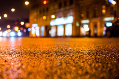 Park yerindeki alışveriş merkezinde yağmurlu bir gece, sıra sıra park edilmiş arabalar..