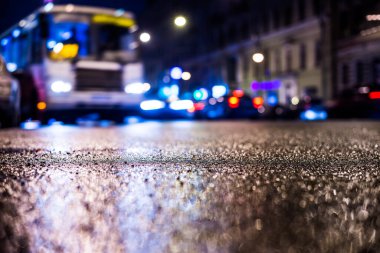 Park yerindeki alışveriş merkezinde yağmurlu bir gece, sıra sıra park edilmiş arabalar..