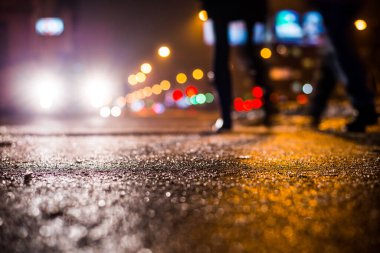 Park yerindeki alışveriş merkezinde yağmurlu bir gece, sıra sıra park edilmiş arabalar..