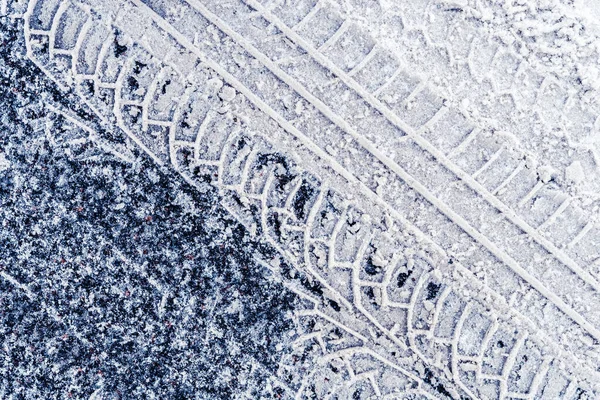 アスファルト上の雪の中で車のタイヤの図の痕跡 — ストック写真