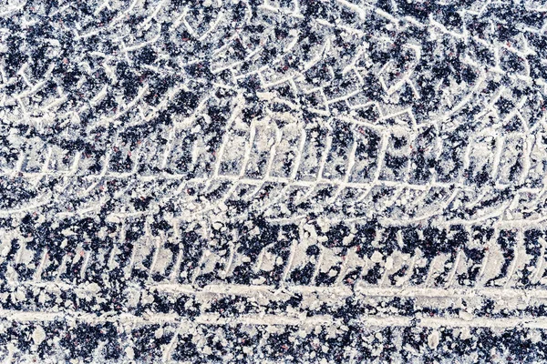 アスファルト上の雪の中で車のタイヤの複数のトレース — ストック写真