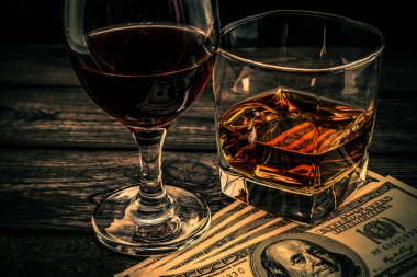 Bir bardak brendi ve kırmızı şarap Eski ahşap bir masada para ile. 