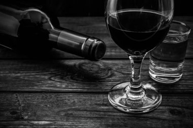 Eski ahşap bir masada bir şişe kırmızı şarap ve tekila..