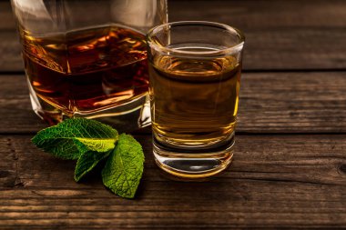 Glass of brandy and tequila with mint sprig on an old wooden table
