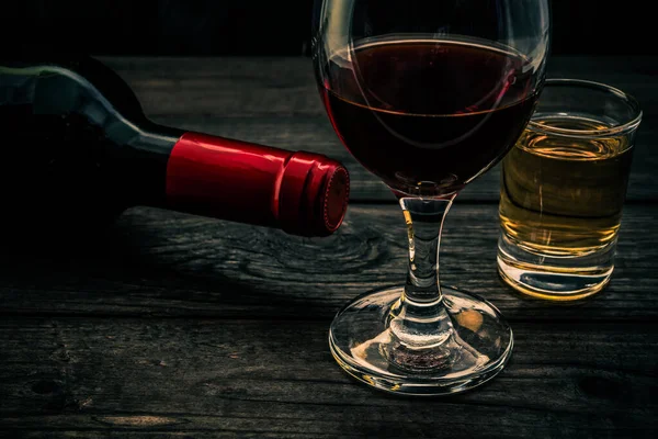 古い木製のテーブルの上に赤ワインとテキーラのガラスとボトル — ストック写真