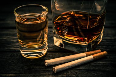 Glass of brandy and tequila with cigarettes on an old wooden table