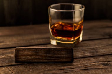 Eski ahşap bir masanın üzerinde boş ahşap bir kalasla bir bardak brendi.