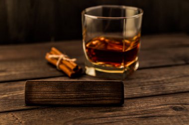 Bir bardak brendi ve jüt halatla bağlanmış tarçın çubukları.