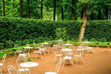 Şehir bahçesindeki ağaçların arasında bir çitin arkasındaki yazlık kafe.
