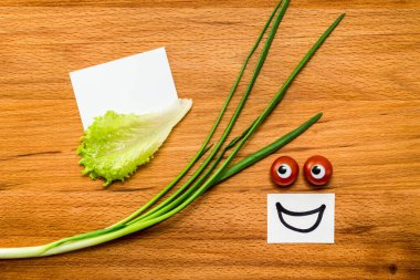 Domates gözler gülümsüyor ve boş kartlara marulla bakıyor.