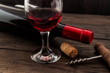 Bir şişe kırmızı şarap, bir kadeh kırmızı şarap ve mantarlı mantar.