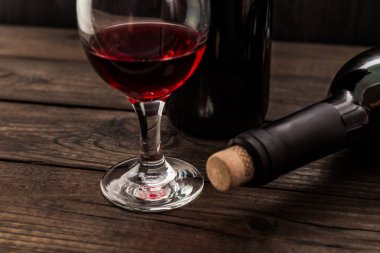 Eski ahşap bir masada iki şişe kırmızı şarap..