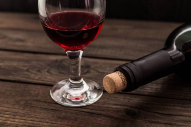 Eski ahşap bir masada bir şişe kırmızı şarap..