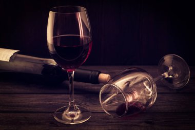 Bottle of red wine with two glasses on an old wooden table. Focu