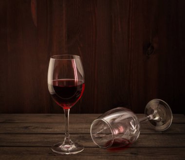 Two glasses of red wine on an old wooden table.