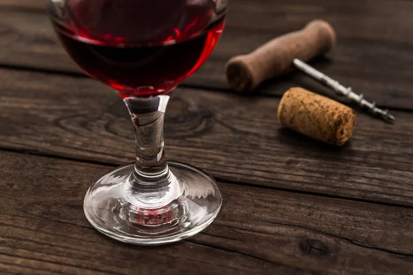 古い木製のテーブルの上にコルクと赤ワインとコルク栓のガラス — ストック写真