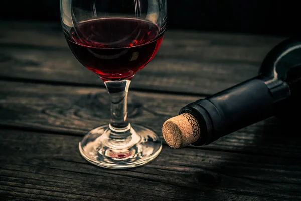 古い木製のテーブルの上にガラスと赤ワインのボトル — ストック写真