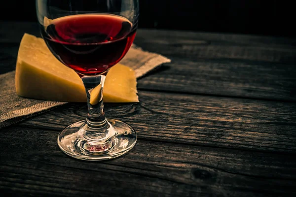 古い木製のテーブルの上にパルメザンチーズと赤ワインのグラス — ストック写真