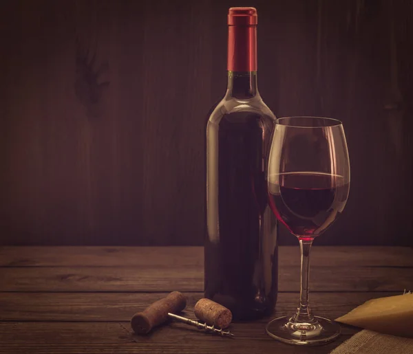 古い木製のテーブルの上にパルメザンチーズとガラスとコルク栓付きの赤ワインのボトル — ストック写真