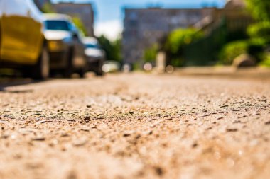 Şehirde güneşli bir gün, park halindeki arabalarla şehir avlusunda yol.