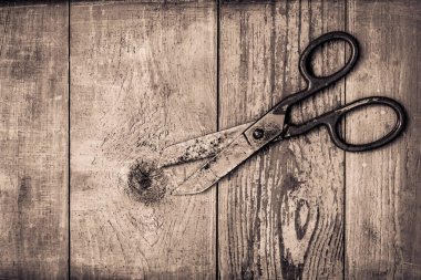 Eski ahşap masada mavi boyayla kaplı paslı ve eski bir makas.