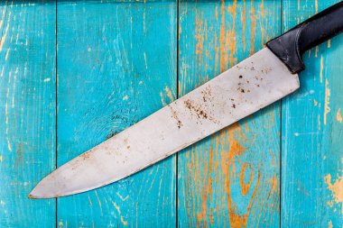 Eski ahşap masadaki paslı ve eski bıçak mavi boyayla kaplıydı..