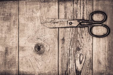 Eski ahşap masada mavi boyayla kaplı paslı ve eski bir makas.