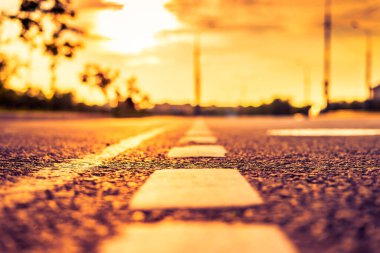 Şehirde gün batımı, park etmiş arabaların olduğu boş yol..