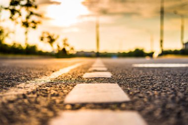 Şehirde gün batımı, park etmiş arabaların olduğu boş yol..