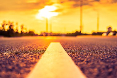 Şehirde gün batımı, park etmiş arabaların olduğu boş yol..