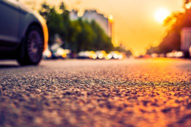 Şehirde gün batımı, park etmiş arabaların olduğu boş yol..