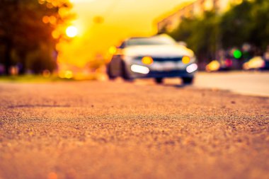 Şehirde gün batımı, park etmiş arabaların olduğu boş yol..