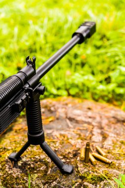 Tüfek, kayanın üzerinde boş kabukları olan bir bipod üzerinde duruyor.