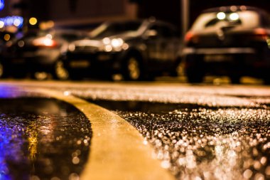 Büyük şehirde yağmurlu bir gece, su birikintileri olan boş bir yol.