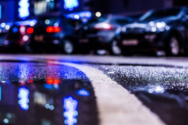 Park yerindeki alışveriş merkezinde yağmurlu bir gece, sıra sıra park edilmiş arabalar..