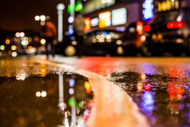 Büyük şehirde yağmurlu bir gece, su birikintileri olan boş bir yol.