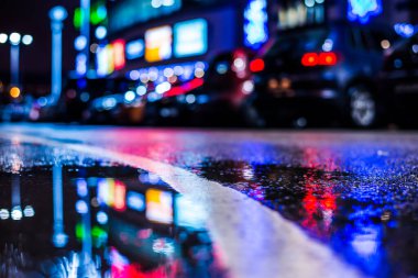 Büyük şehirde yağmurlu bir gece, su birikintileri olan boş bir yol.