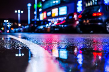 Büyük şehirde yağmurlu bir gece, su birikintileri olan boş bir yol.