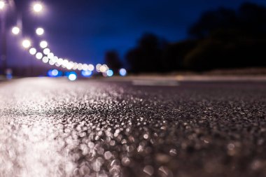 Park yerindeki alışveriş merkezinde yağmurlu bir gece, sıra sıra park edilmiş arabalar..