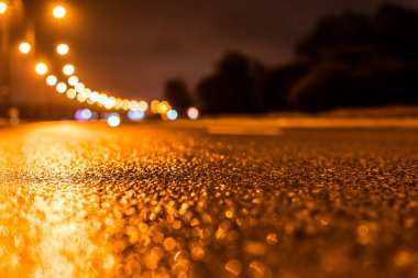 Park yerindeki alışveriş merkezinde yağmurlu bir gece, sıra sıra park edilmiş arabalar..