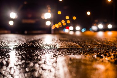 Park yerindeki alışveriş merkezinde yağmurlu bir gece, sıra sıra park edilmiş arabalar..