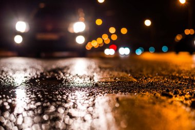 Park yerindeki alışveriş merkezinde yağmurlu bir gece, sıra sıra park edilmiş arabalar..