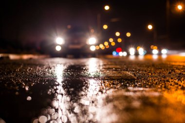 Park yerindeki alışveriş merkezinde yağmurlu bir gece, sıra sıra park edilmiş arabalar..