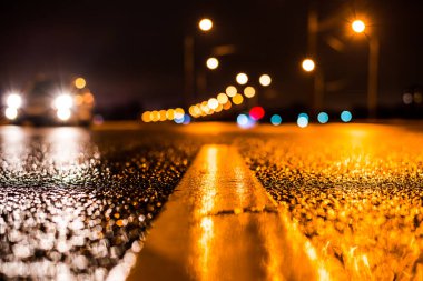 Park yerindeki alışveriş merkezinde yağmurlu bir gece, sıra sıra park edilmiş arabalar..