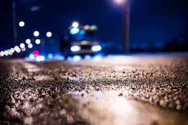 Park yerindeki alışveriş merkezinde yağmurlu bir gece, sıra sıra park edilmiş arabalar..