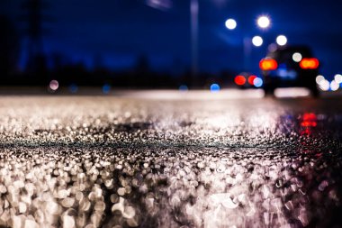 Büyük şehirde yağmurlu bir gece, su birikintileri olan boş bir yol.