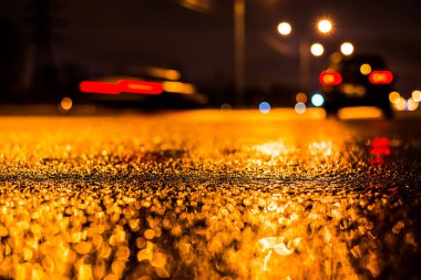 Park yerindeki alışveriş merkezinde yağmurlu bir gece, sıra sıra park edilmiş arabalar..