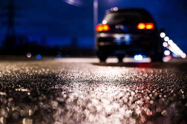 Büyük şehirde yağmurlu bir gece, su birikintileri olan boş bir yol.