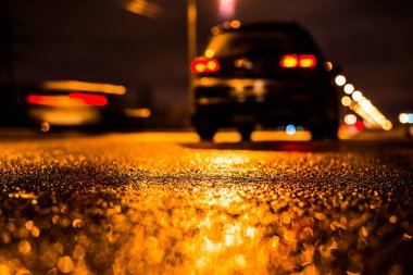 Park yerindeki alışveriş merkezinde yağmurlu bir gece, sıra sıra park edilmiş arabalar..