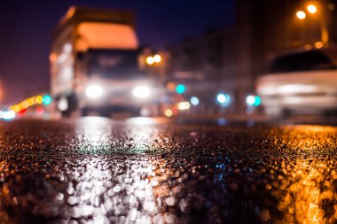 Park yerindeki alışveriş merkezinde yağmurlu bir gece, sıra sıra park edilmiş arabalar..